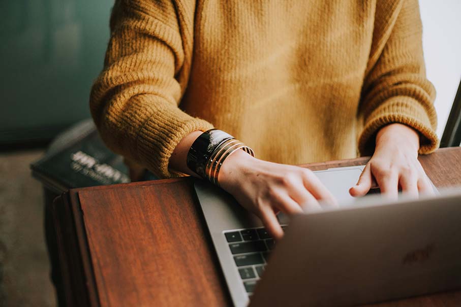 A woman engaged in typing on a laptop, showcasing concentration and productivity in a modern workspace