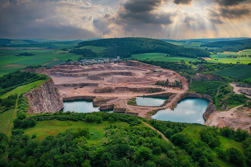 Aerial view of a quarry with water, trees, open pit mine, and tailings ponds