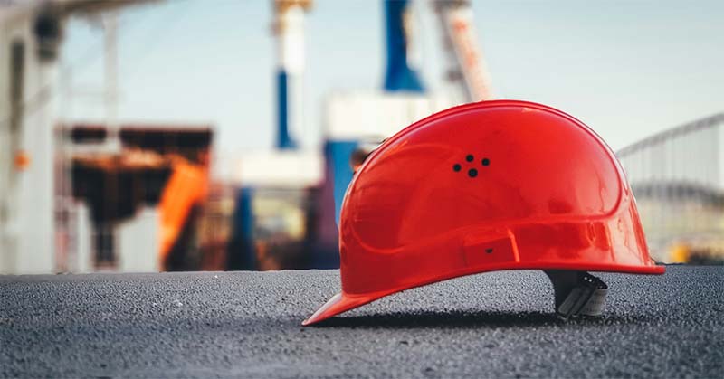 red hardhat with an industrial site in the background