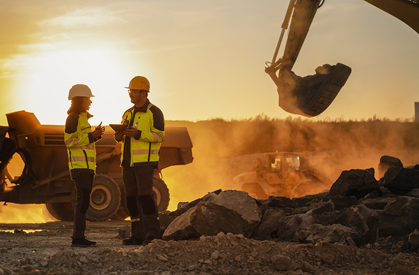 Two construction workers posing in front of a bulldozer at a mine site