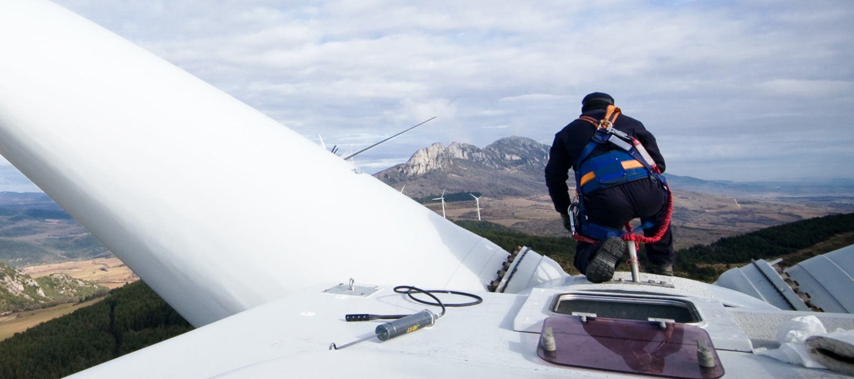 Lone worker kneeling on top of a wind turbine
